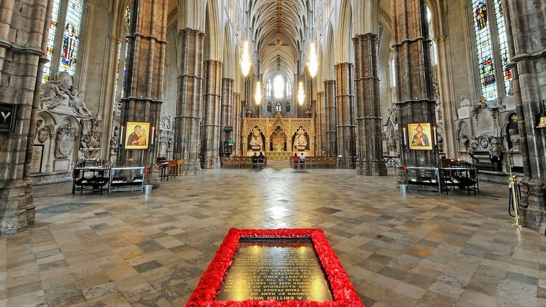 Tomb of the Unknown Soldier surrounded by poppies inside Westminster Abbey, London.