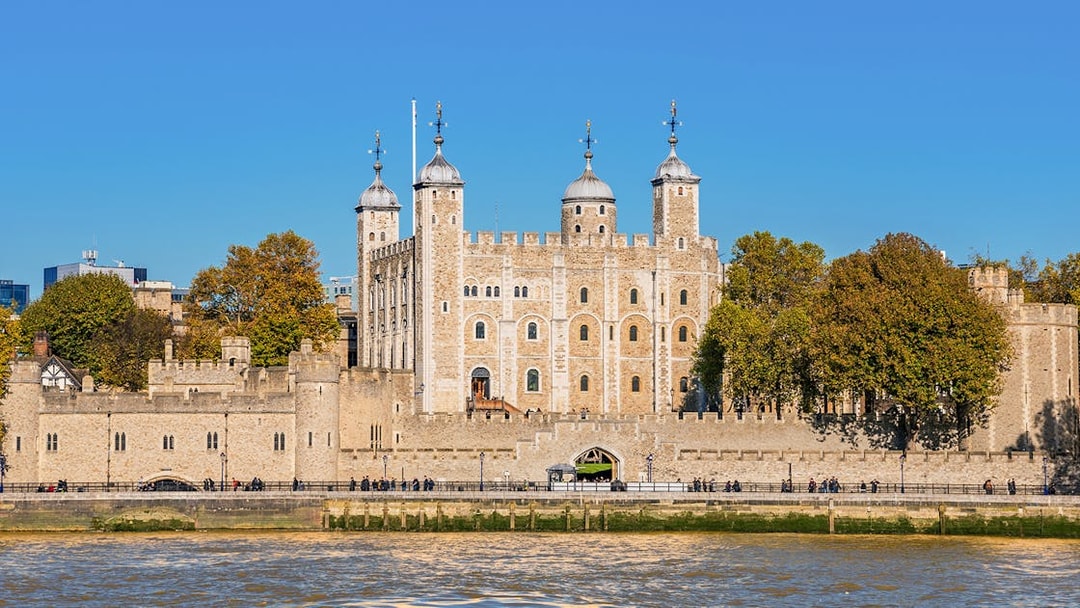 Tower of London exterior with river view and surrounding trees.