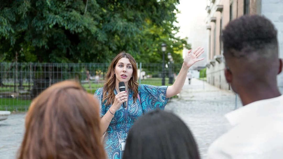 Tour guide speaking to tourists in a park setting.