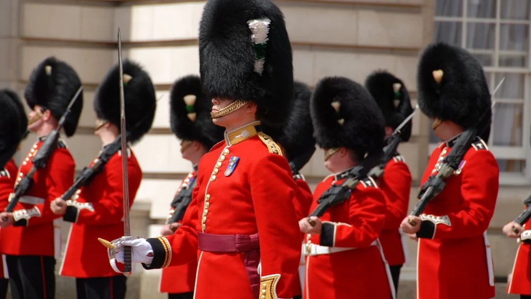 British guards in red uniforms and bearskin hats during a ceremonial event.