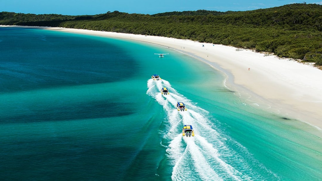 Rafting boats and seaplane over turquoise waters near Whitsundays beach.