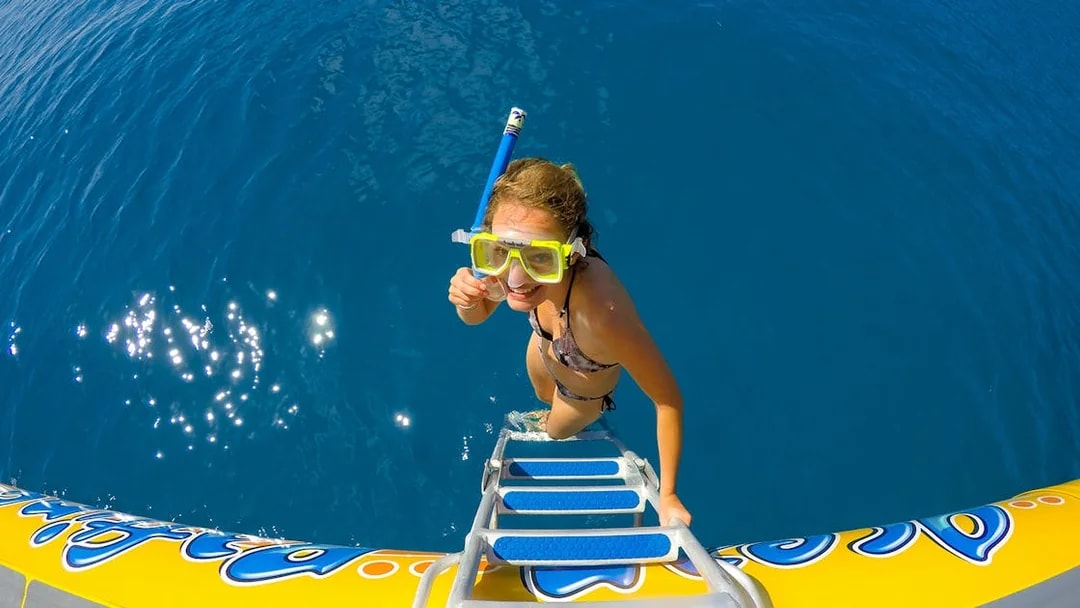 Snorkeler climbing onto raft in Whitsundays Fly + Raft Package tour.