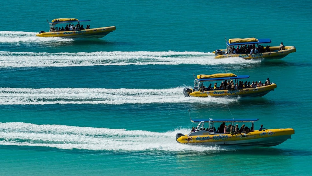 Speedboats with tourists on Whitsundays Fly + Raft Package tour in turquoise waters.