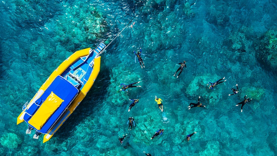 Snorkelers near a yellow raft in clear Whitsundays waters, Australia.