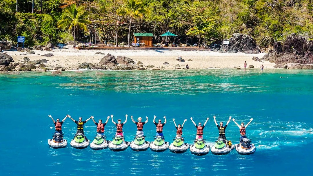 Tourists on jetskis in formation near Whitsundays beach, aerial view.