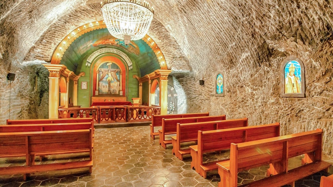 Wieliczka Salt Mine chapel interior with wooden benches and ornate altar.