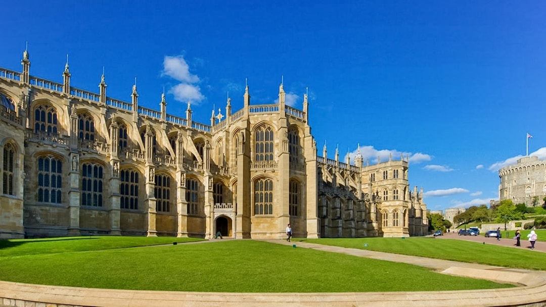 St George’s Chapel exterior with blue sky and green lawn, Windsor Castle in background.
