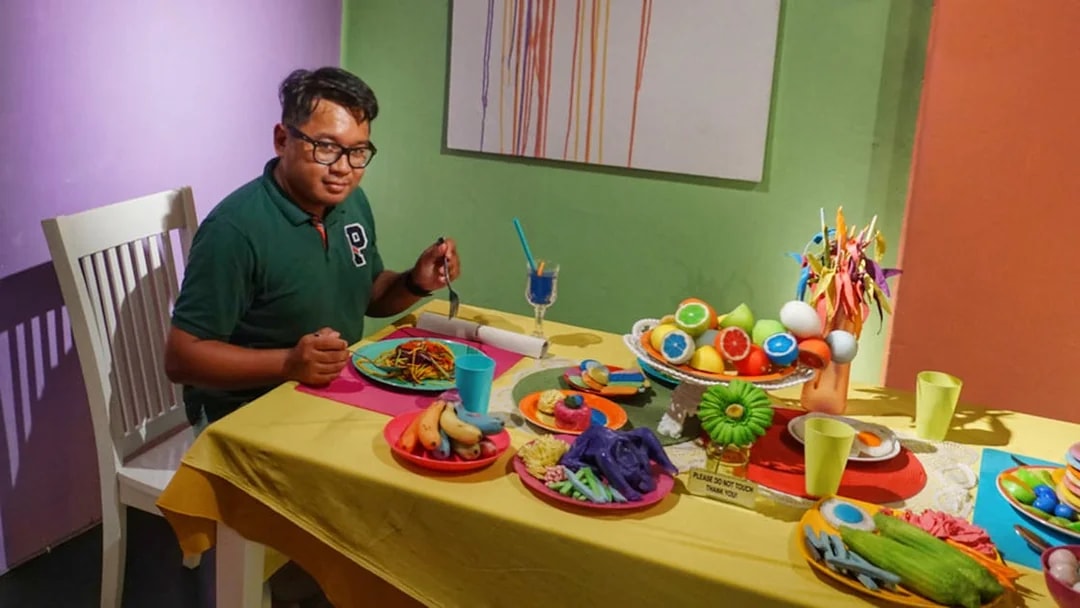 Man seated at a table with colorful food displays at Wonderfood Museum.