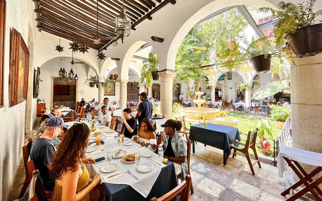 Dining area at Hotel Mesón del Marqués in Valladolid, Yucatán, with guests seated near a courtyard fountain.
