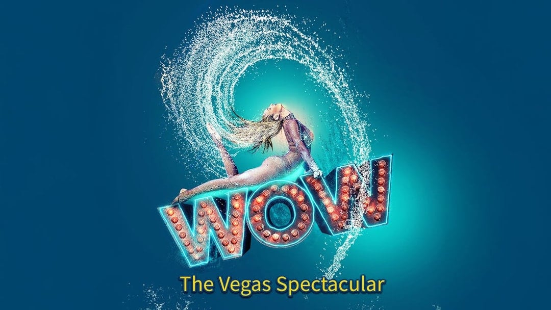 Performer in mid-air pose with water splash, "WOW" sign, Vegas show.