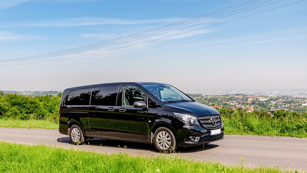 Black van on a scenic road, used for Auschwitz Birkenau AC transfer.
