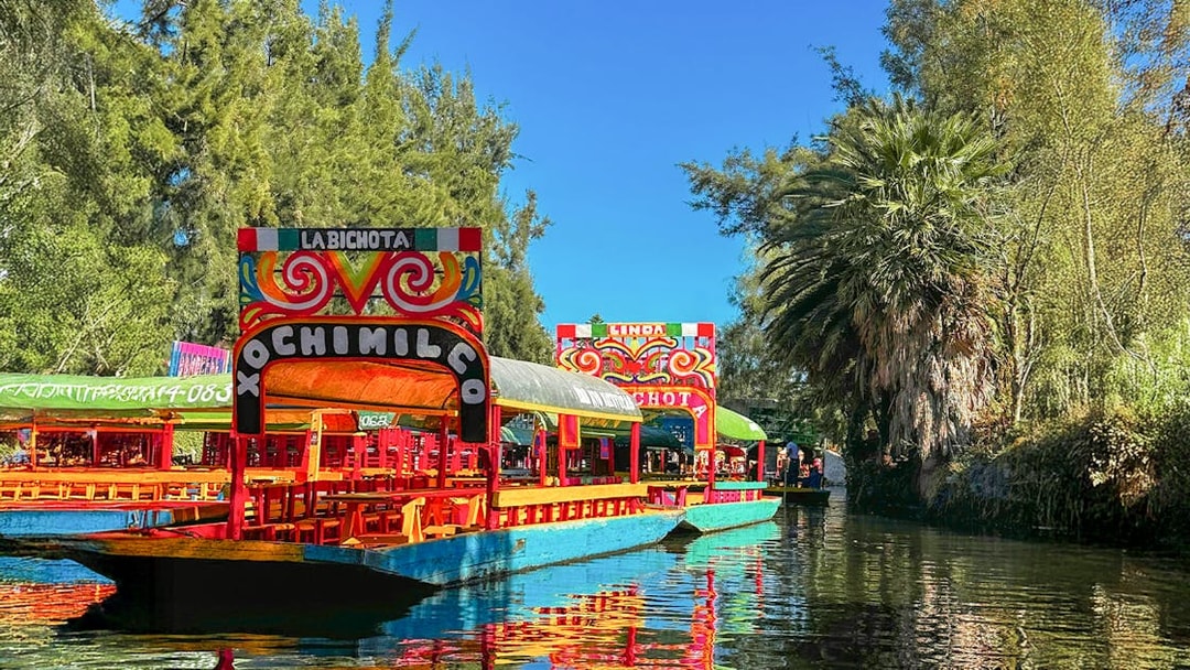 Trajinera boats on Xochimilco canal, Mexico City, with colorful decorations.