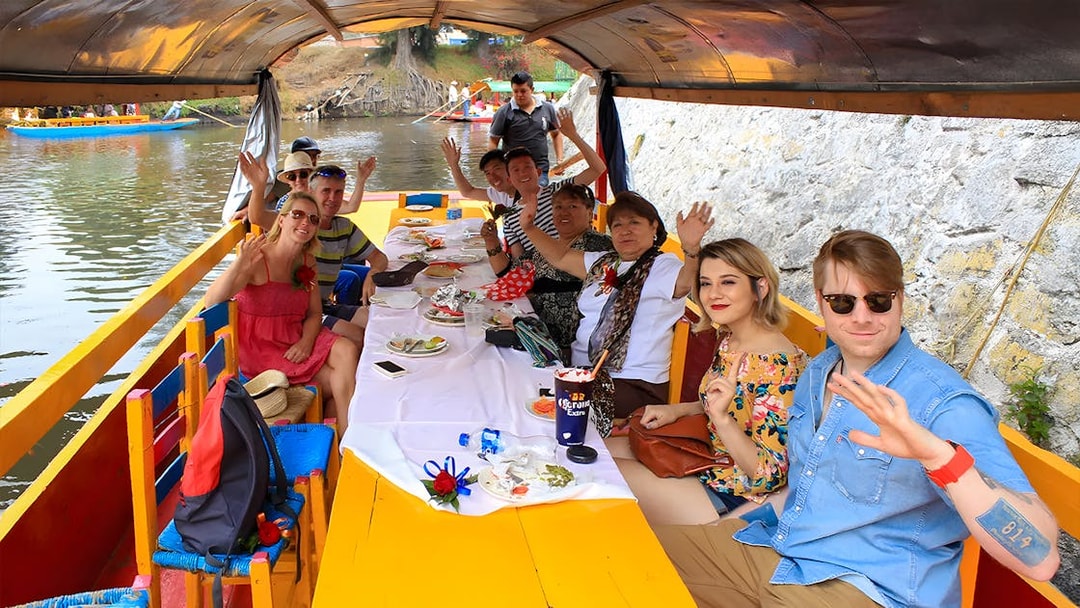 Guests waving on a Trajinera party boat in Xochimilco, Mexico.