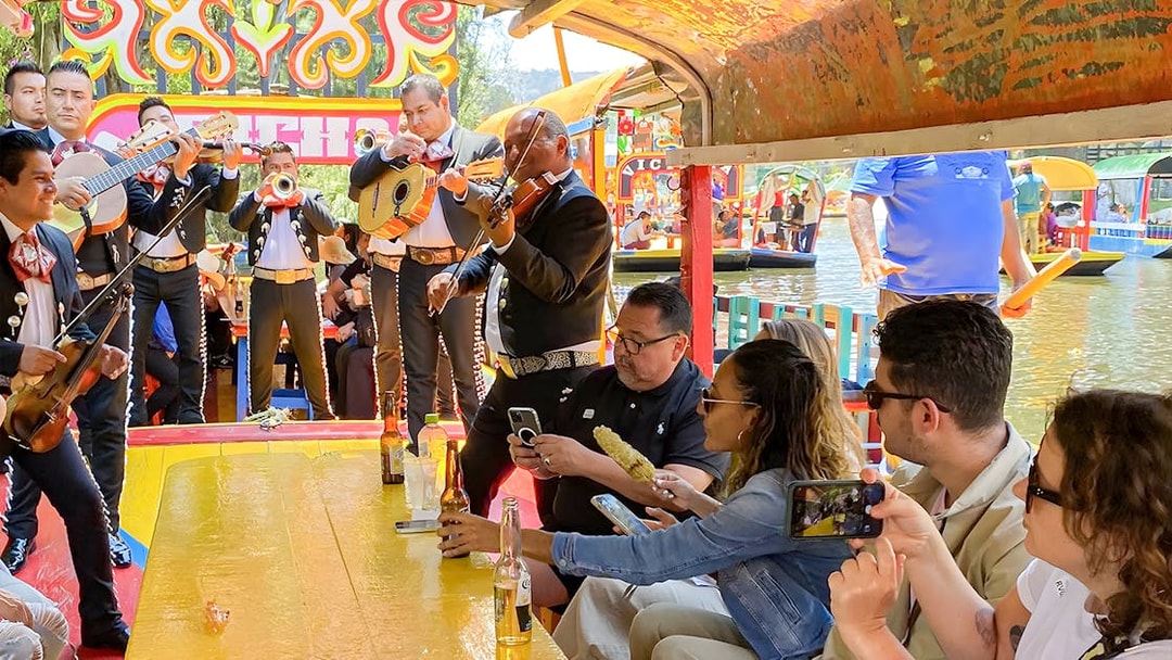 Guests enjoying mariachi band on Trajinera Party boat in Xochimilco, Mexico.