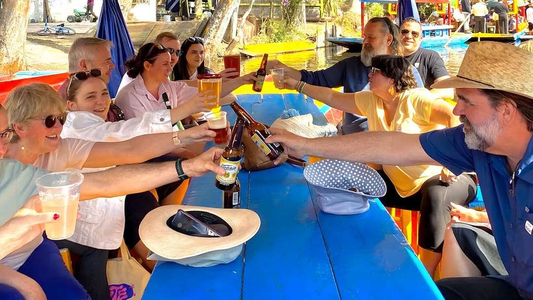 Guests toasting with drinks on a Trajinera party boat in Xochimilco.