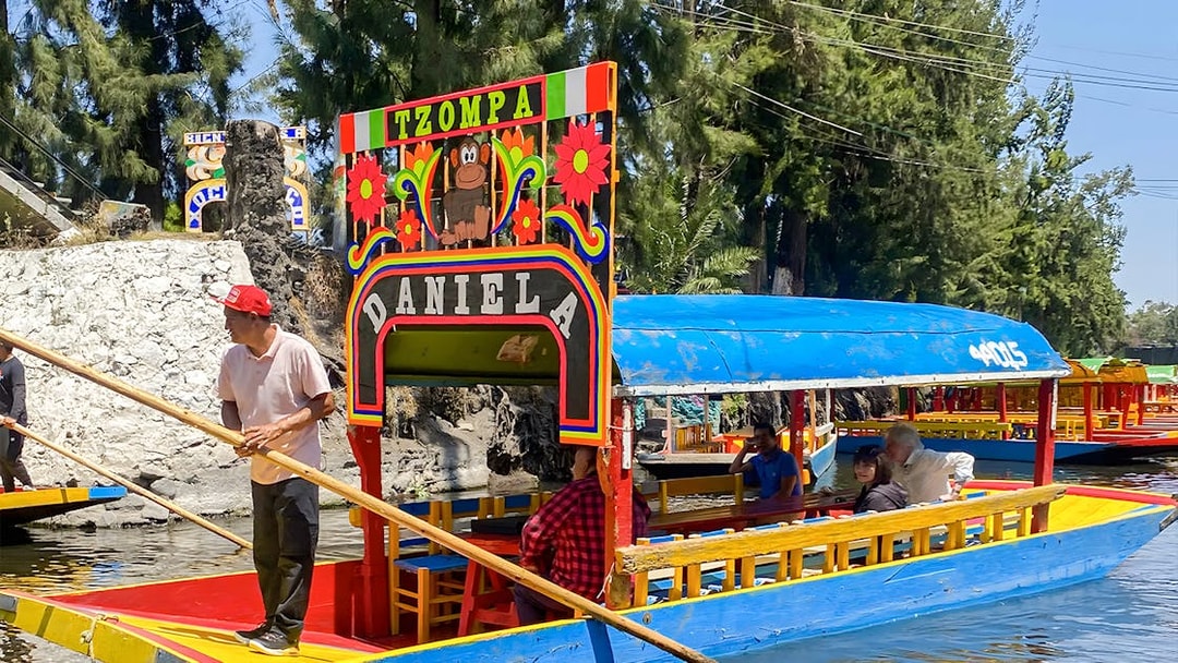 Trajinera boat with passengers on Xochimilco canal, Mexico City.