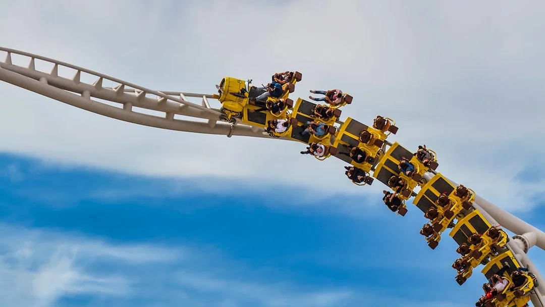 Roller coaster at Ferrari World Abu Dhabi with riders on a loop against blue sky.