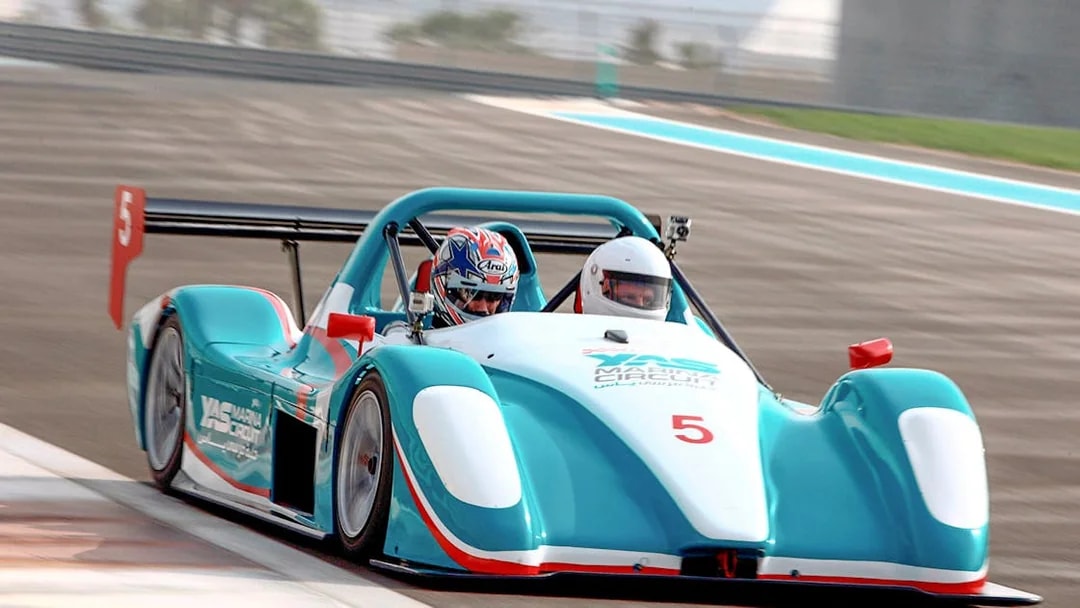Racing car with two passengers on Yas Marina Circuit track.