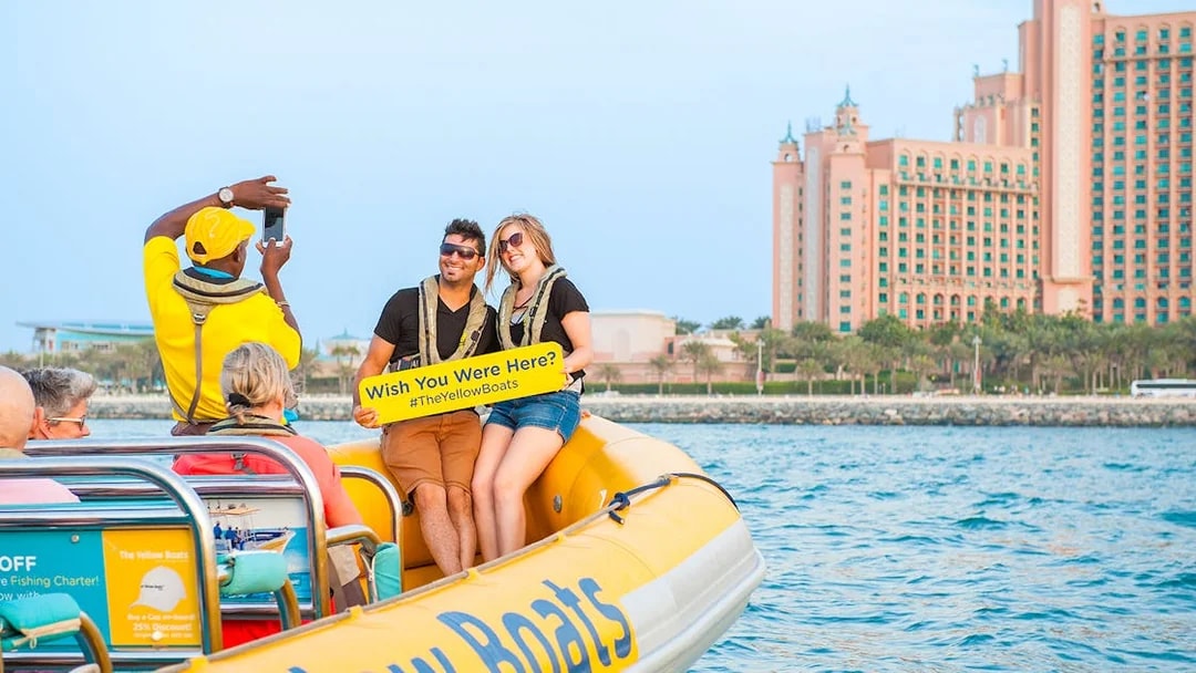 Couple on Dubai speedboat tour with Atlantis hotel in background.
