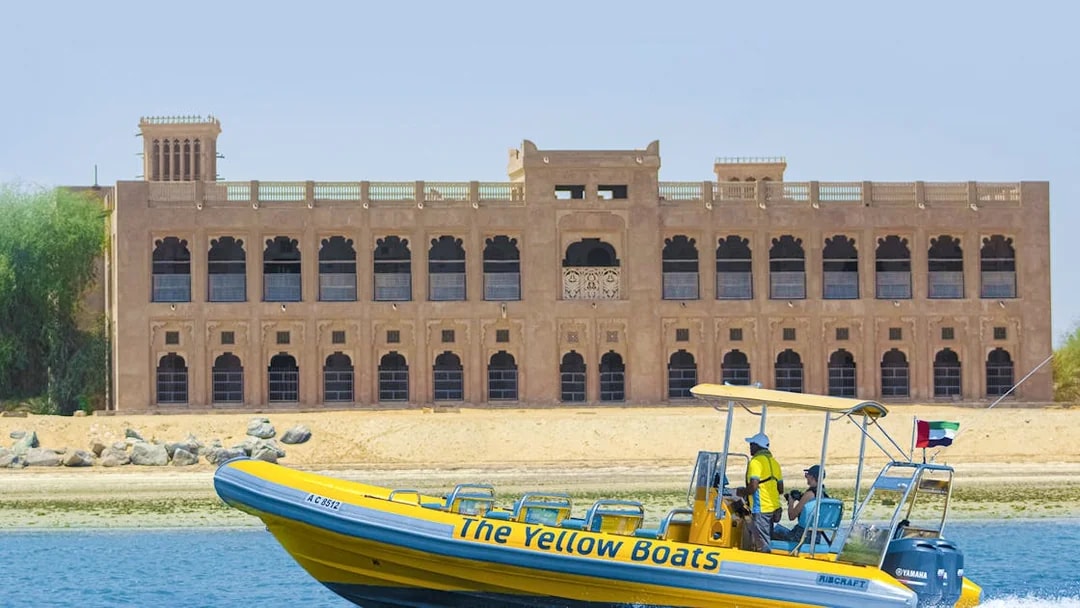 Yellow speedboat touring Yas Island with historic building in background.