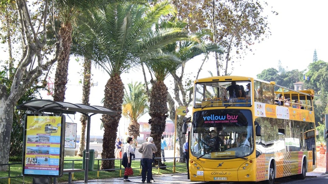 Open-top yellow bus at Funchal stop for 48-hour hop-on hop-off tour.