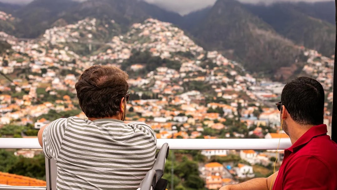 Tourists on a Funchal bus tour overlooking the cityscape and mountains.