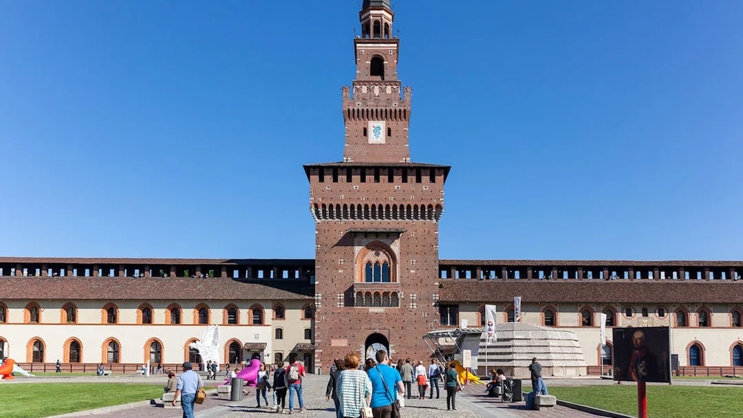Visitors walking towards Sforza Castle courtyard in Milan, Italy.