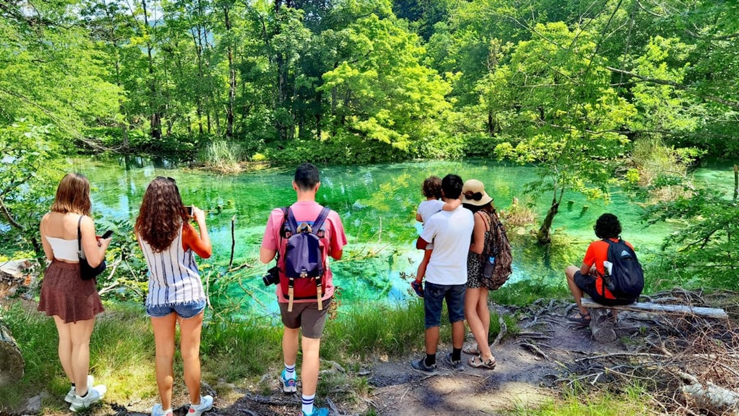 Tourists enjoying the view of a turquoise lake at Plitvice Lakes National Park.