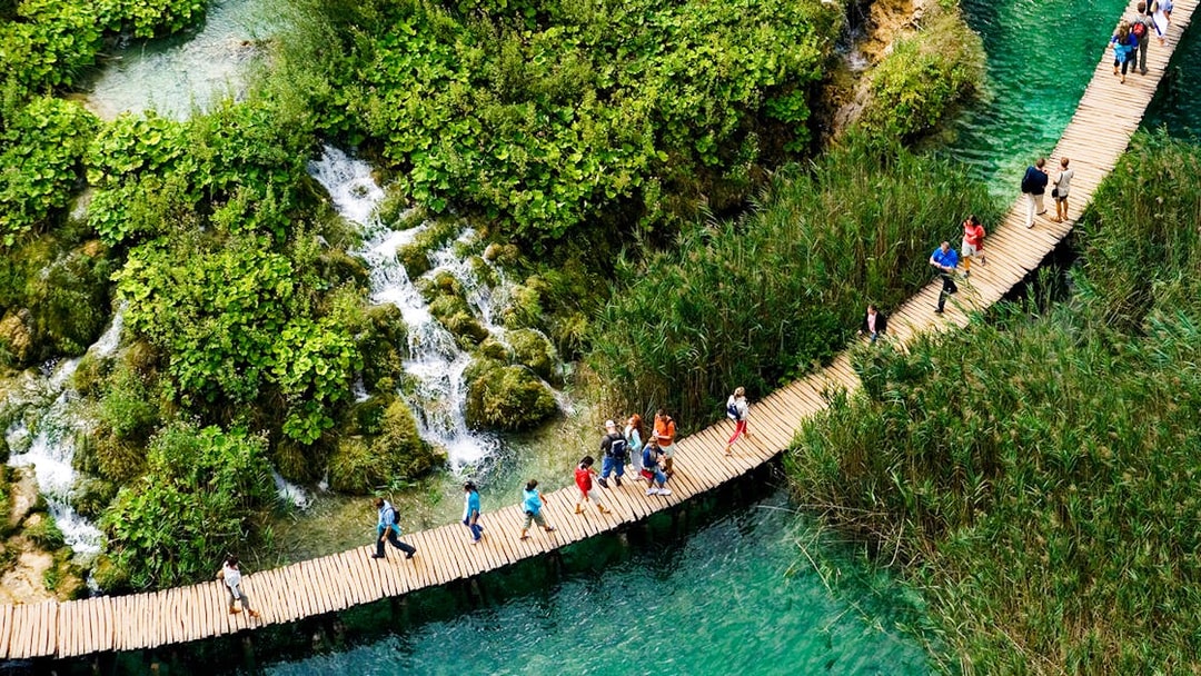 Visitors walking on a wooden path over turquoise water at Plitvice Lakes, Croatia.