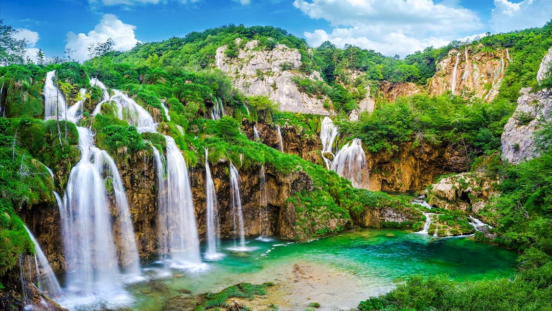 Waterfalls cascading into a turquoise lake at Plitvice Lakes National Park, Croatia.