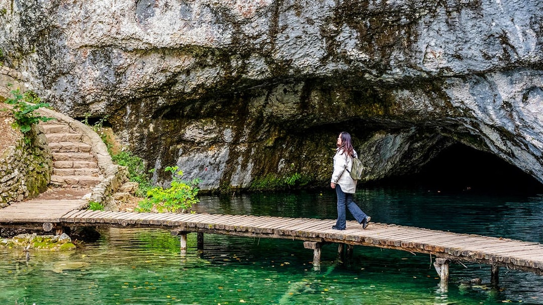 Female walking on wooden deck over turquoise water at Plitvice Lakes, Croatia.