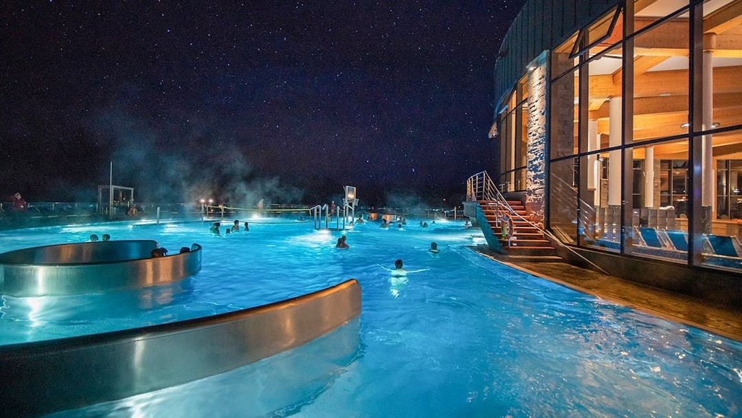 Visitors enjoying Chocholow Thermal Baths at night under a starry sky.