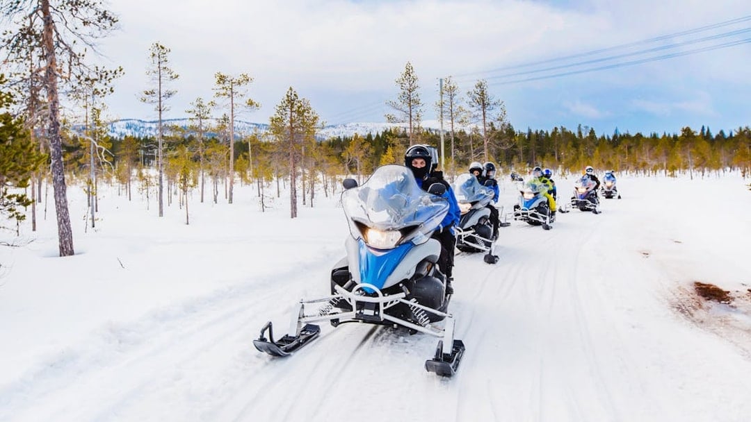 Snowmobilers riding through snowy forest near Zakopane, Poland.