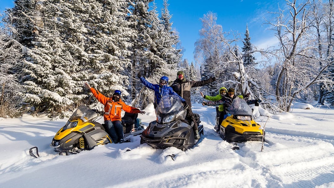 Visitors enjoying snowmobiles in snowy Zakopane forest.