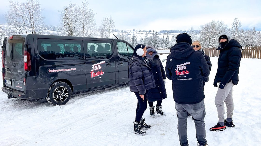 Group by a van in snowy landscape for roundtrip AC private transfers.