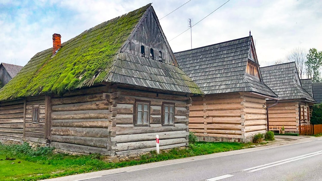 Traditional wooden houses in Zakopane along a road, part of the snowmobile tour with thermal baths.