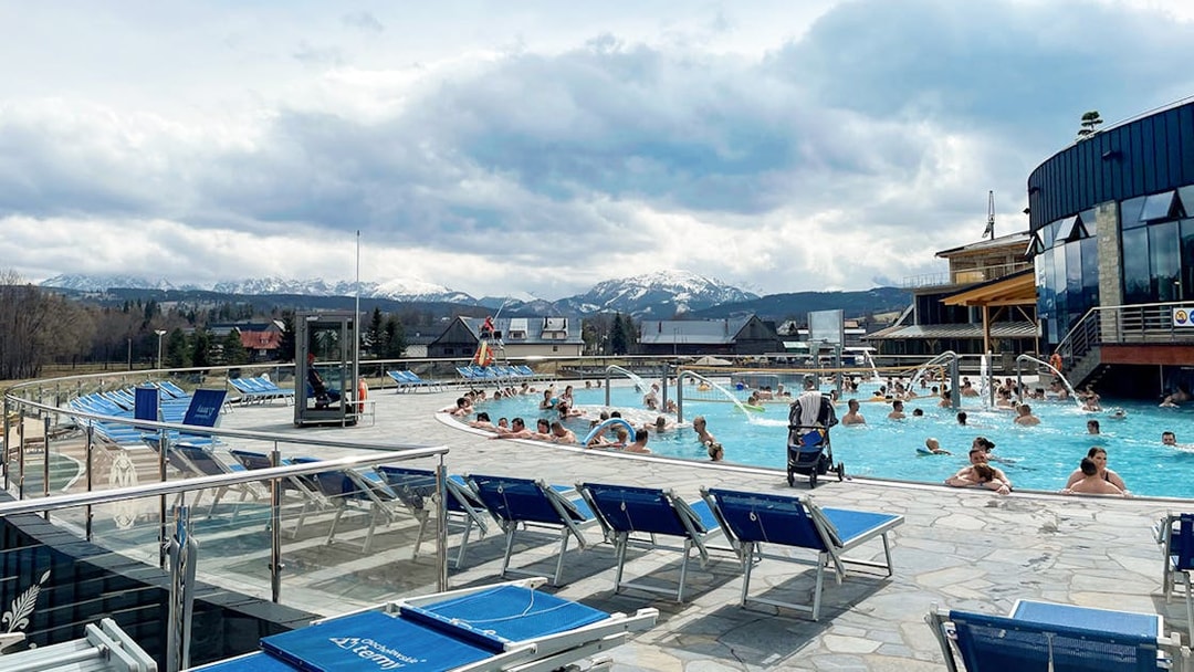 Visitors enjoying outdoor pools at Chocholowskie Thermal Bath with mountain views.