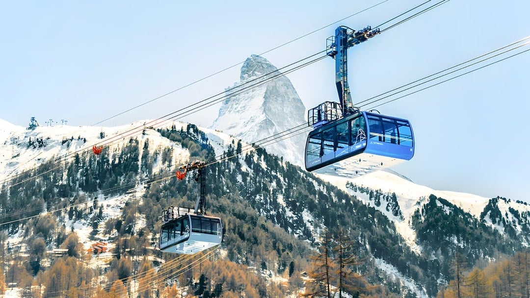 Cable cars ascending to Matterhorn Glacier Paradise with snowy mountain backdrop.
