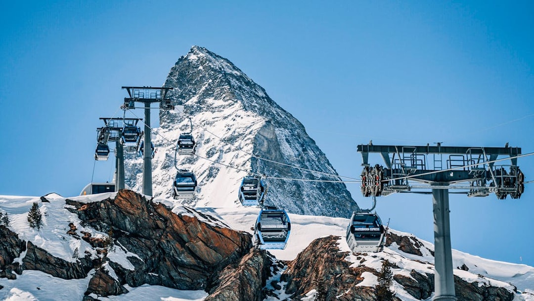 Cable cars traveling to Matterhorn Glacier Paradise with snowy mountain backdrop.