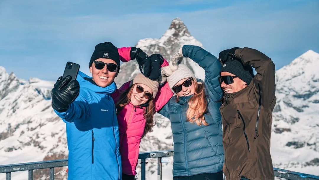 Group taking a selfie on a snowy mountain viewing platform.