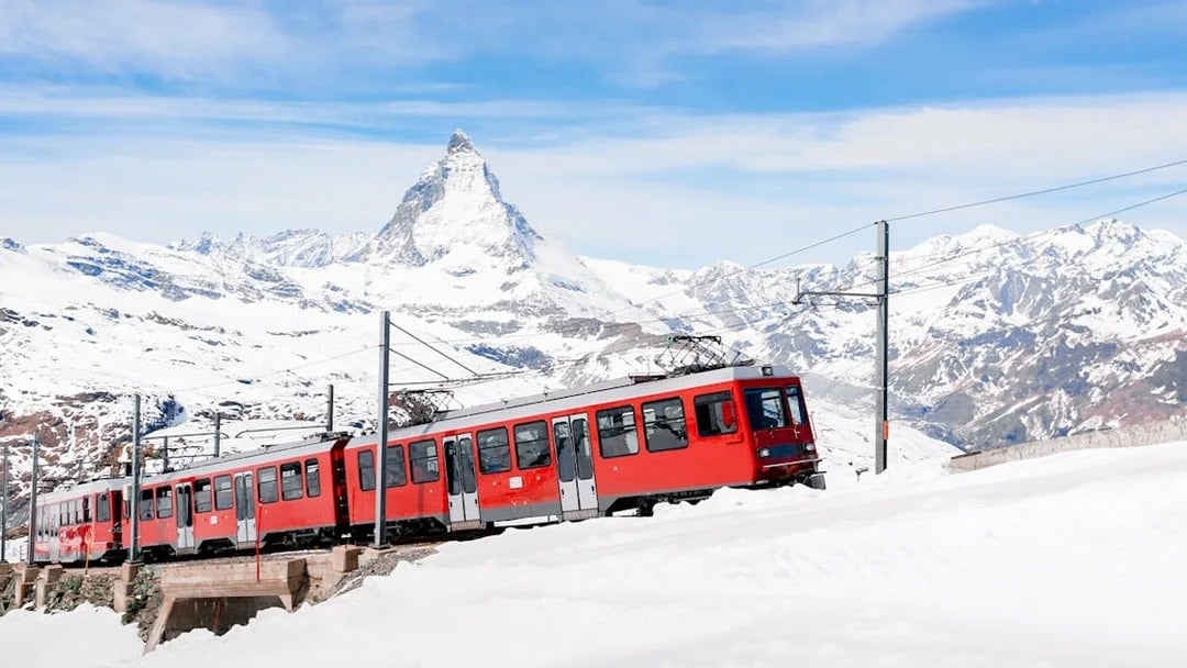 Gornergratbahn train approaching Gornergrat station with Matterhorn in the background.